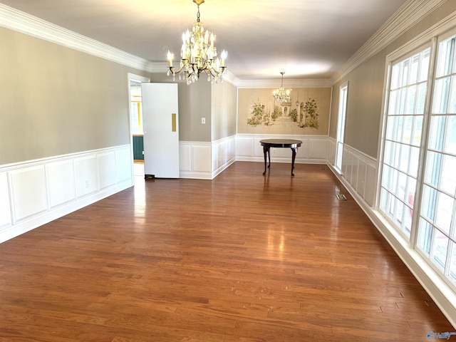 unfurnished dining area featuring crown molding, dark wood finished floors, visible vents, a decorative wall, and a chandelier