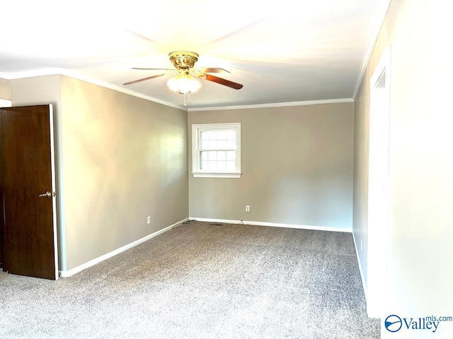 carpeted spare room featuring ceiling fan, baseboards, and crown molding