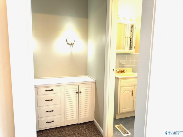 bathroom featuring visible vents, backsplash, and vanity