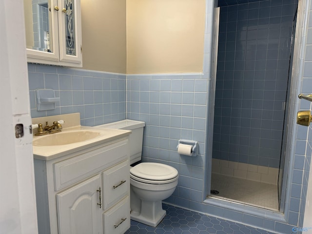 full bath featuring a stall shower, toilet, tile patterned floors, vanity, and tile walls