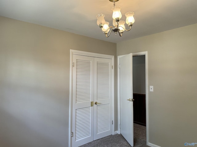 unfurnished bedroom featuring a chandelier, a closet, dark carpet, and baseboards