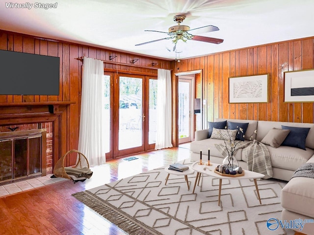 living room featuring french doors, a fireplace, wood walls, and wood finished floors