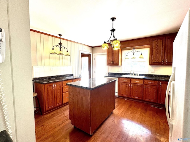 kitchen featuring dark wood finished floors, freestanding refrigerator, a kitchen island, a sink, and dishwashing machine