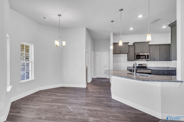 kitchen with sink, appliances with stainless steel finishes, decorative light fixtures, and dark hardwood / wood-style floors