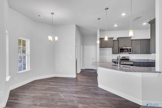 kitchen featuring light stone countertops, stainless steel appliances, dark wood-type flooring, and a sink