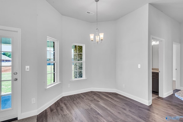 unfurnished dining area with dark wood finished floors, a chandelier, visible vents, and baseboards