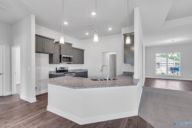 kitchen with stone counters, stainless steel appliances, sink, kitchen peninsula, and dark hardwood / wood-style flooring