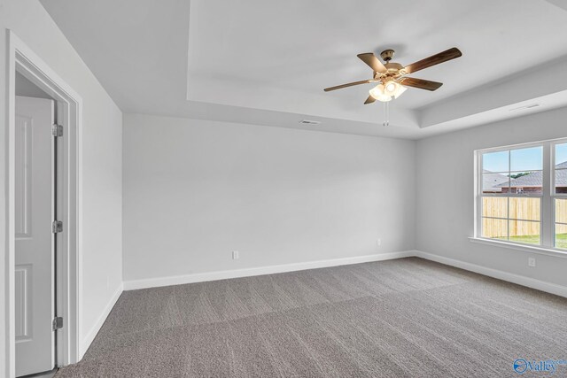 unfurnished room featuring carpet flooring, ceiling fan, and a raised ceiling