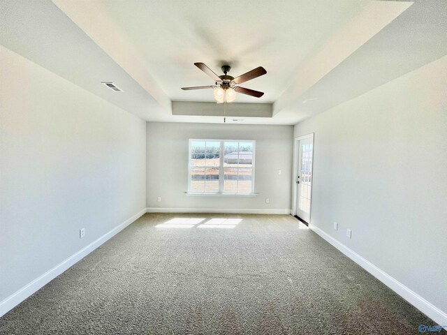 empty room with a healthy amount of sunlight, carpet, visible vents, baseboards, and a tray ceiling