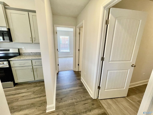 corridor with visible vents, light wood-type flooring, and baseboards