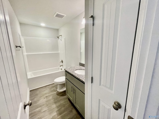 bathroom featuring vanity, wood finished floors, visible vents, bathing tub / shower combination, and toilet