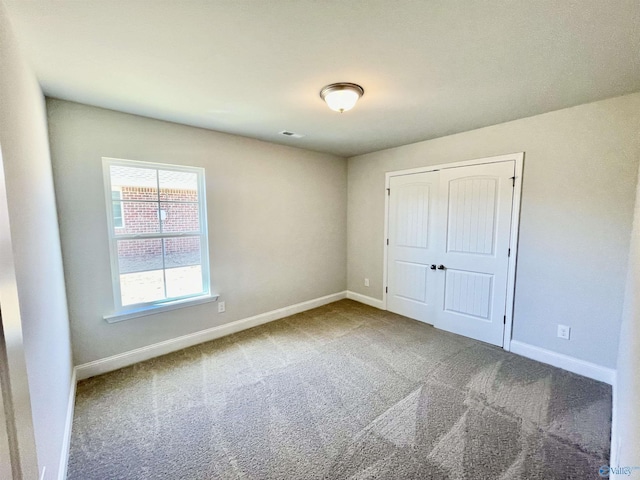 unfurnished bedroom with a closet, carpet flooring, visible vents, and baseboards