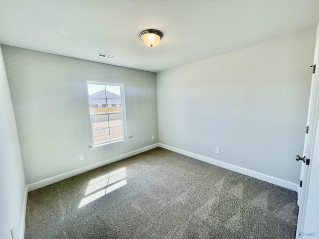 spare room with carpet flooring, baseboards, and visible vents