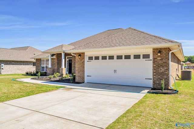 view of front of home with a garage, central AC, and a front yard