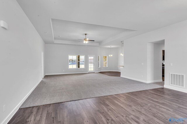 unfurnished living room with wood-type flooring, ceiling fan, and a tray ceiling