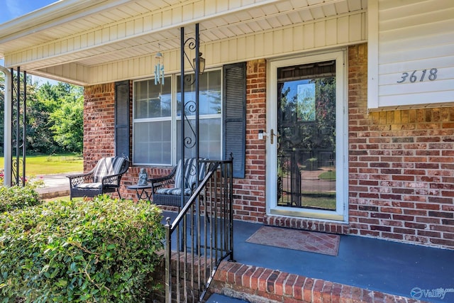 property entrance with covered porch and brick siding