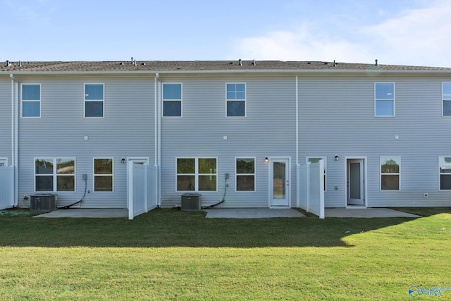 rear view of property featuring central AC unit, a patio, and a lawn