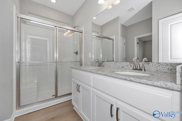 bathroom featuring hardwood / wood-style flooring, vanity, and an enclosed shower