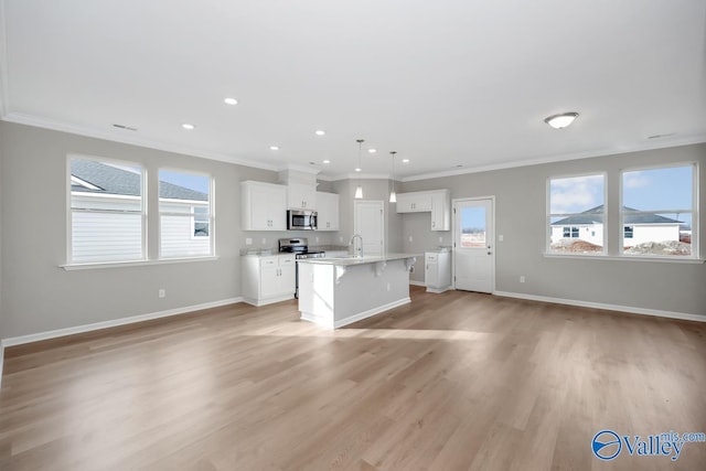 kitchen featuring an island with sink, a wealth of natural light, appliances with stainless steel finishes, and hanging light fixtures