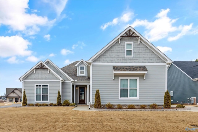 craftsman house featuring a front yard and roof with shingles