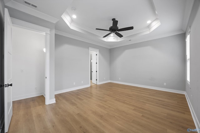 unfurnished room with ceiling fan, ornamental molding, a raised ceiling, and light hardwood / wood-style floors