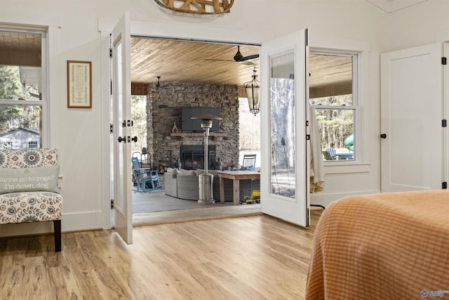 bedroom featuring access to outside, wood ceiling, a fireplace, and wood finished floors