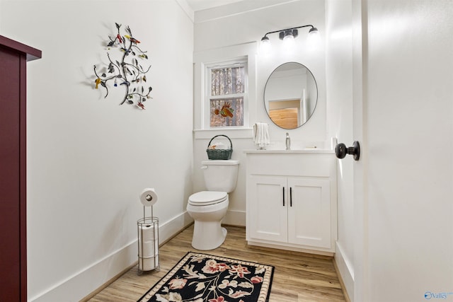 bathroom featuring vanity, wood finished floors, toilet, and baseboards