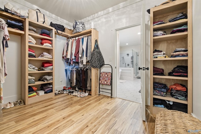 walk in closet with light wood finished floors