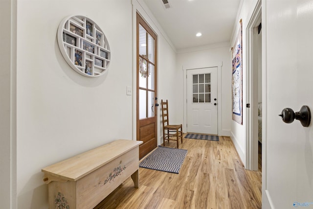 doorway to outside featuring light wood finished floors, visible vents, baseboards, ornamental molding, and recessed lighting