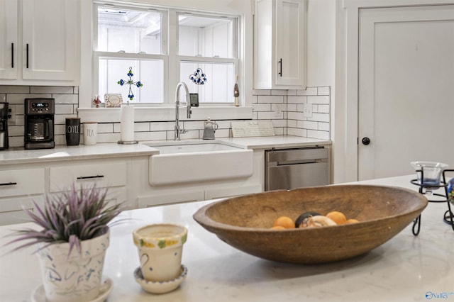 kitchen with a sink, white cabinets, light countertops, backsplash, and dishwasher