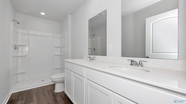 bathroom featuring a shower, wood-type flooring, vanity, and toilet