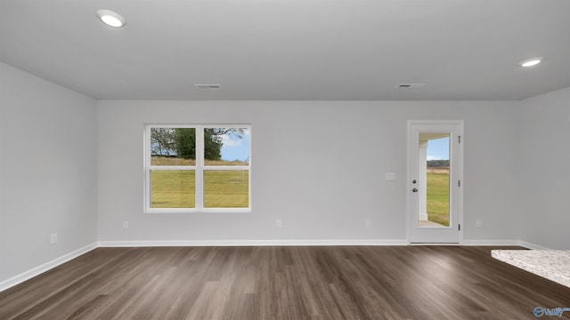 empty room featuring a healthy amount of sunlight and dark wood-type flooring