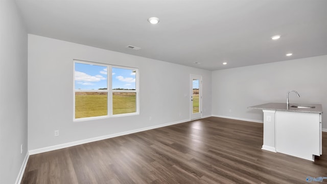 unfurnished living room featuring sink and dark hardwood / wood-style flooring