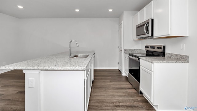 kitchen with sink, light stone counters, appliances with stainless steel finishes, a kitchen island with sink, and white cabinets