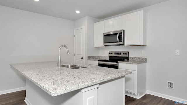 kitchen featuring stainless steel appliances, an island with sink, sink, and white cabinetry