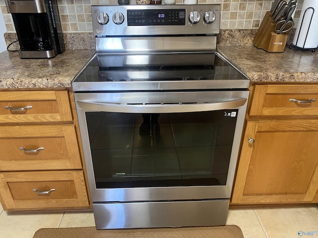 kitchen featuring light tile patterned floors, stainless steel electric stove, and decorative backsplash