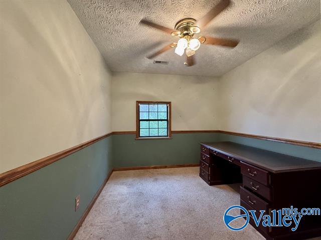 home office with a textured ceiling, light colored carpet, and ceiling fan