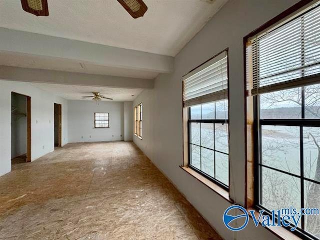 unfurnished room with beam ceiling and ceiling fan