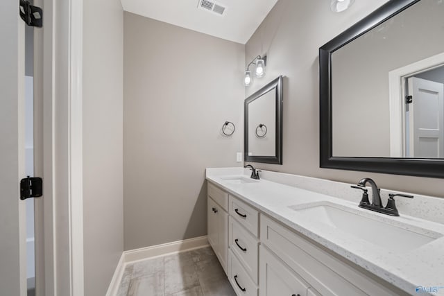 full bath with double vanity, a sink, visible vents, and baseboards