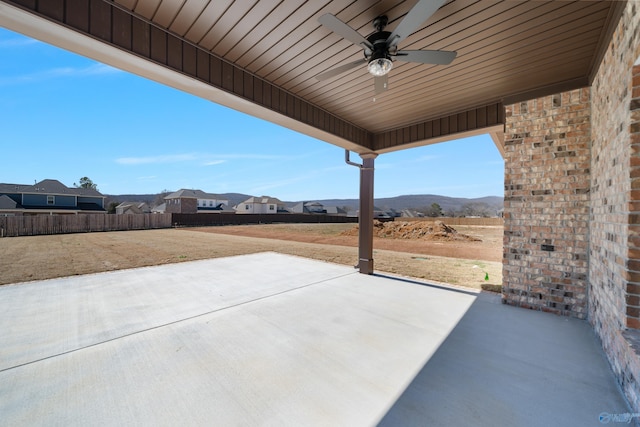 view of patio with a ceiling fan, fence, and a mountain view