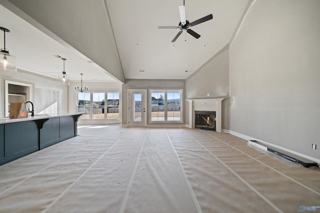 unfurnished living room featuring lofted ceiling, sink, and ceiling fan with notable chandelier