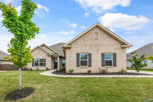 view of front of home with brick siding, a front lawn, and fence