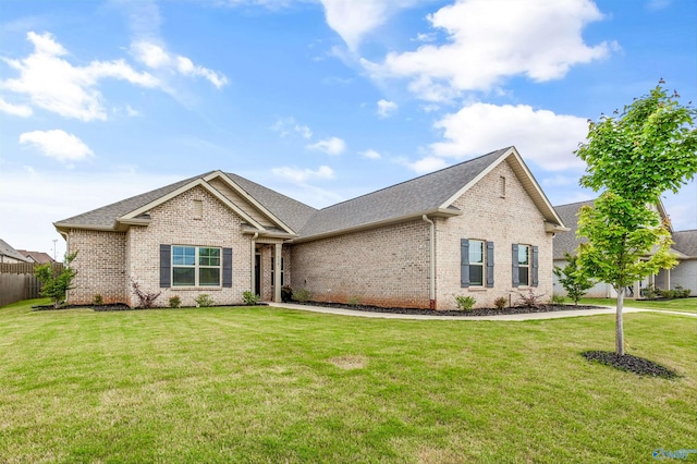 single story home featuring brick siding, fence, a front yard, and roof with shingles