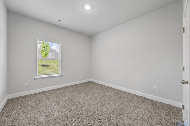 carpeted spare room with visible vents and baseboards