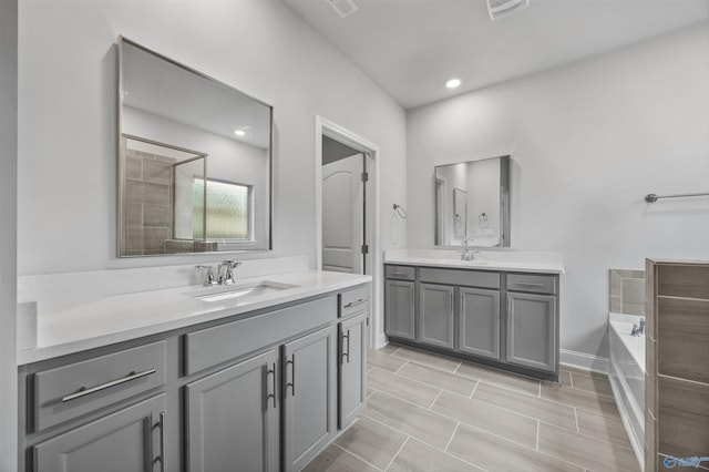 full bath featuring a sink, visible vents, a garden tub, and two vanities