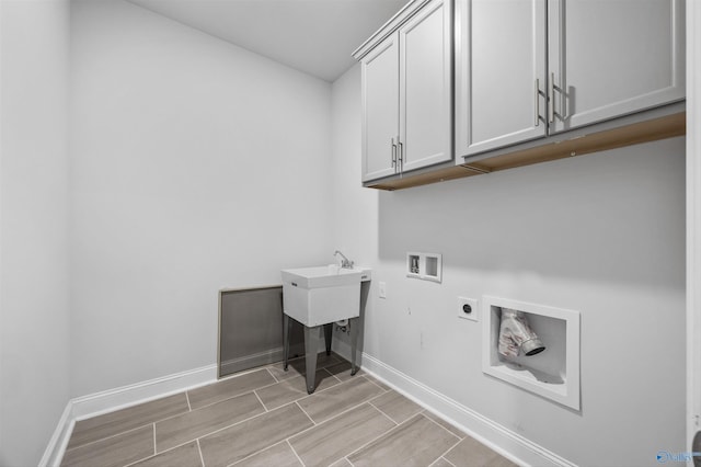 clothes washing area with baseboards, washer hookup, electric dryer hookup, and cabinet space