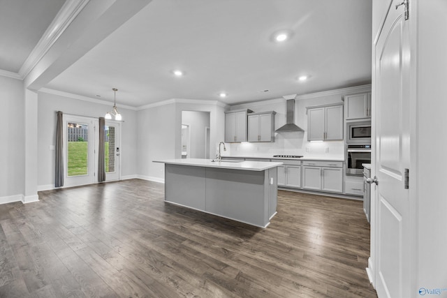 kitchen featuring a sink, dark wood finished floors, wall chimney exhaust hood, stainless steel appliances, and gray cabinetry