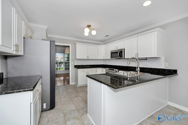 114 Canterbury Dr, Madison, AL 35758 - kitchen with stainless steel appliances, a peninsula, white cabinetry, crown molding, and dark stone countertops