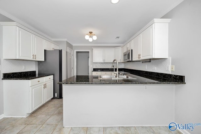 114 Canterbury Dr, Madison, AL 35758 - kitchen featuring appliances with stainless steel finishes, dark stone countertops, a peninsula, white cabinets, and ornamental molding
