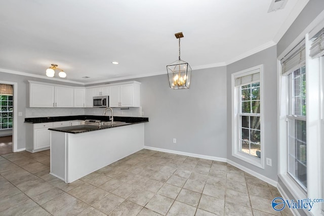 114 Canterbury Dr, Madison, AL 35758 - kitchen featuring stainless steel microwave, a peninsula, a chandelier, dark countertops, and crown molding